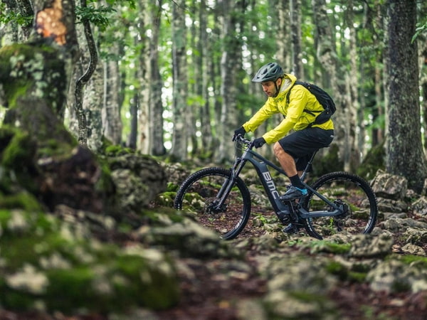 Mountainbiker mit gelber Jacke im Wald